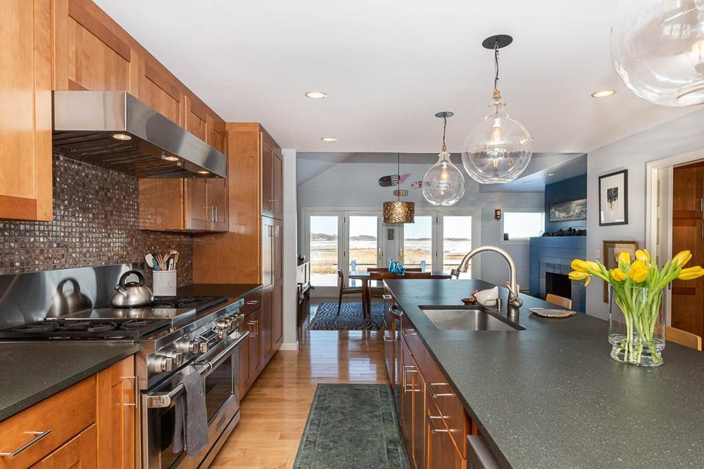 72 Island Road Essex, MA 01929 - Photo 12 of 40 a kitchen with stainless steel appliances granite countertop a stove top oven a dining table and chairs with wooden floor