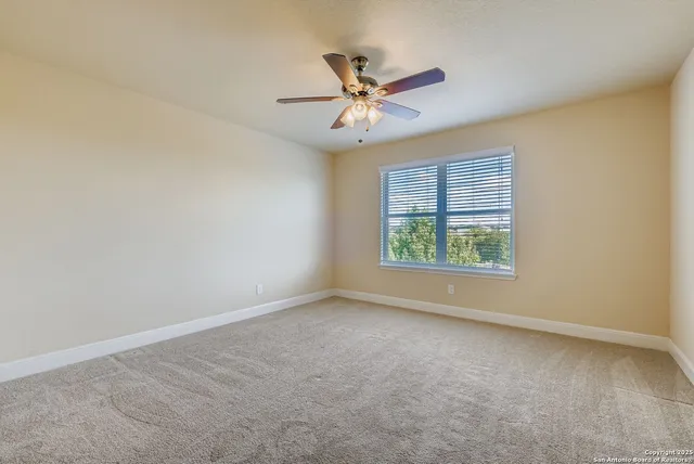 an empty room with a window and a ceiling fan