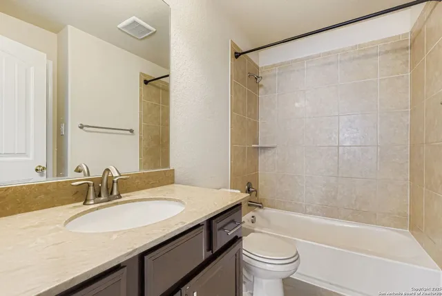 a bathroom with a granite countertop sink a toilet and shower