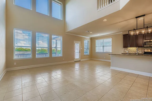 a view of an empty room with kitchen and window