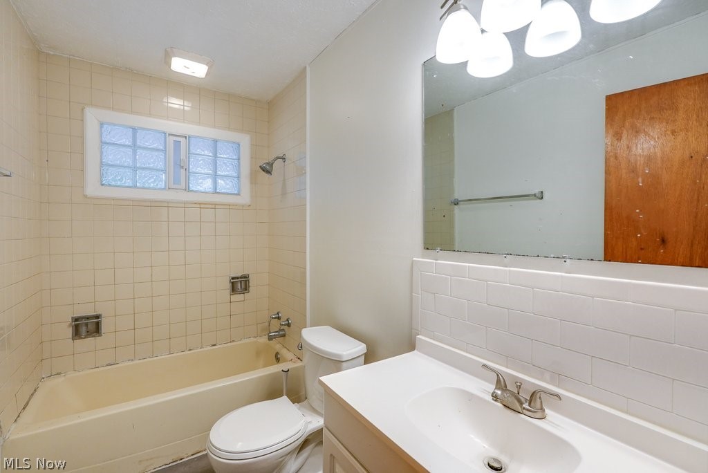 1481 Old Forge Road Mogadore, OH 44260 - Photo 23 of 27 Full bathroom with tile walls, backsplash, toilet, tiled shower / bath, and vanity