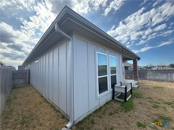 a backyard of a house with outdoor seating and trees in the background