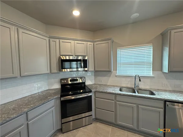 a kitchen with granite countertop a sink stainless steel appliances and cabinets