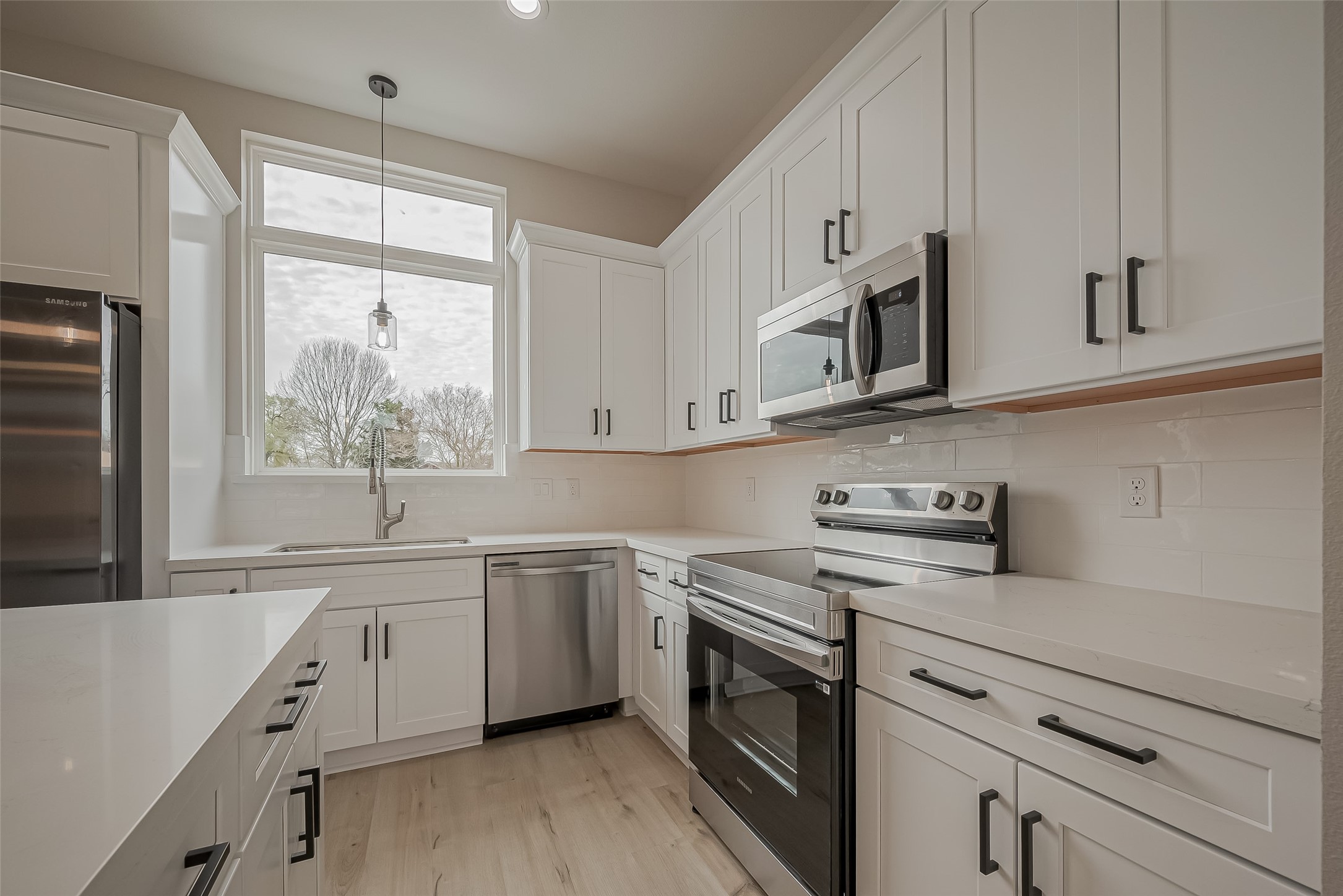 918 St Clair Street, Unit B Houston, TX 77088 - Photo 12 of 35 a kitchen with stainless steel appliances granite countertop white cabinets a sink a stove a window and white appliances