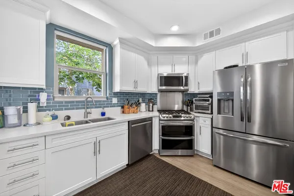 a kitchen with stainless steel appliances a refrigerator sink and microwave