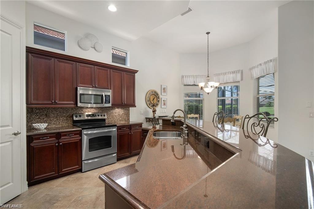 6476 Caldecott Drive Naples, FL 34113 - Photo 5 of 27 a kitchen with stainless steel appliances granite countertop a sink a stove and a wooden floors