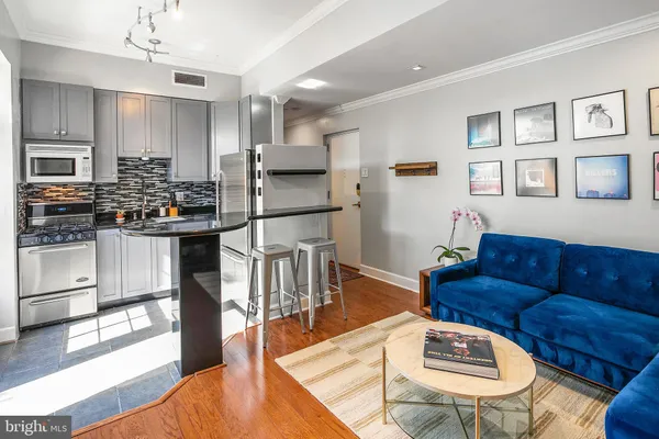 a living room with stainless steel appliances kitchen island granite countertop furniture and a wooden floor