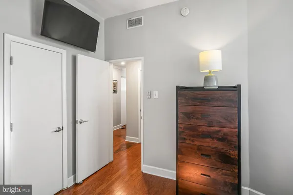 a view of a hallway with wooden floor and cabinet