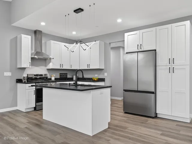 a kitchen with stainless steel appliances granite countertop a sink a stove and a wooden floors