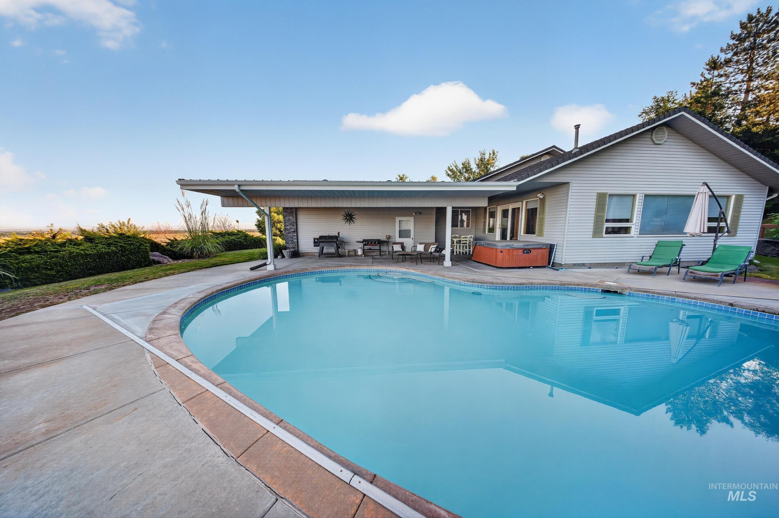 5540 Finley Road Fruitland, ID 83619 - Photo 24 of 50 C-shaped swimming pool with a concrete surround, covered patio, and attached spa