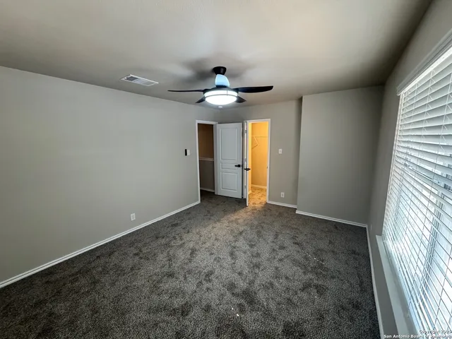 an empty room with windows and fan