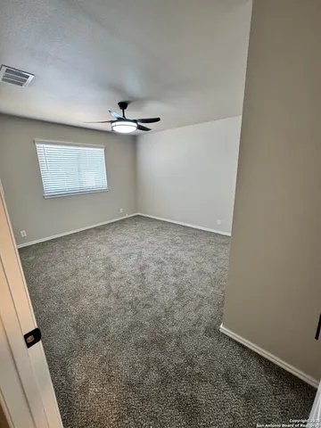 an empty room with a window and a ceiling fan