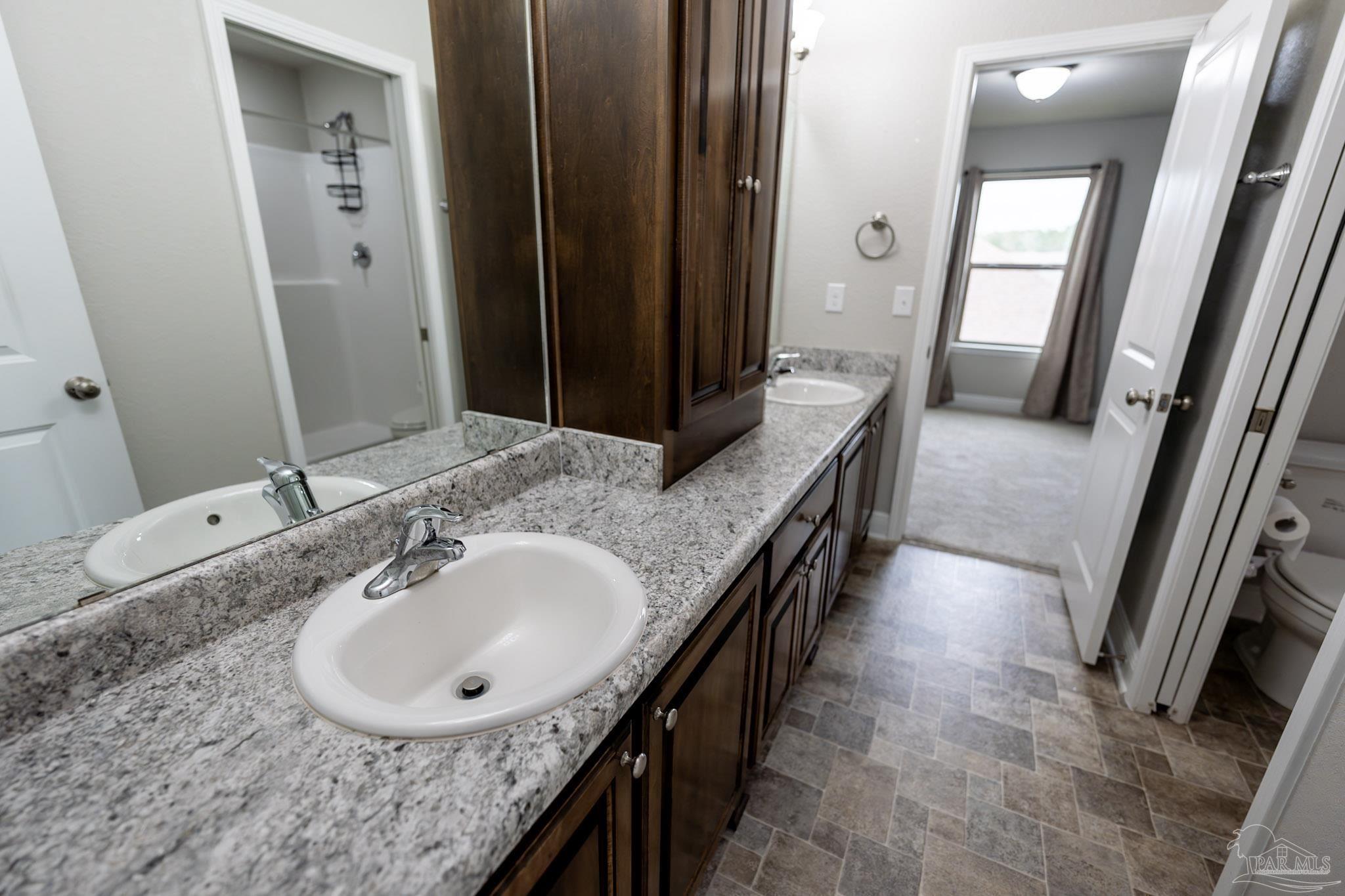 1060 Bretts Way Cantonment, FL 32533 - Photo 27 of 32 a bathroom with a granite countertop sink a mirror and a shower