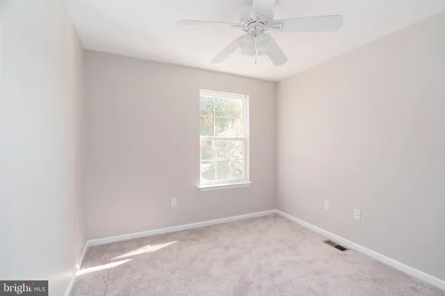 an empty room with a window and a fan
