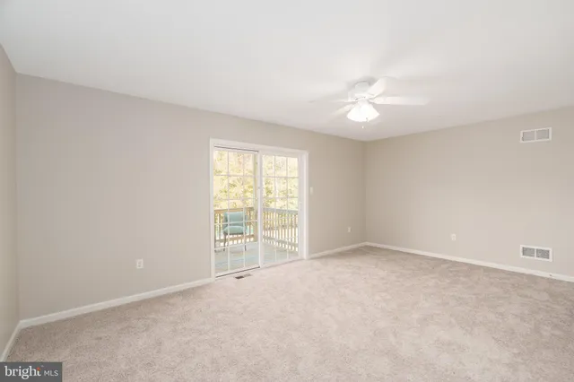 an empty room with windows and ceiling fan