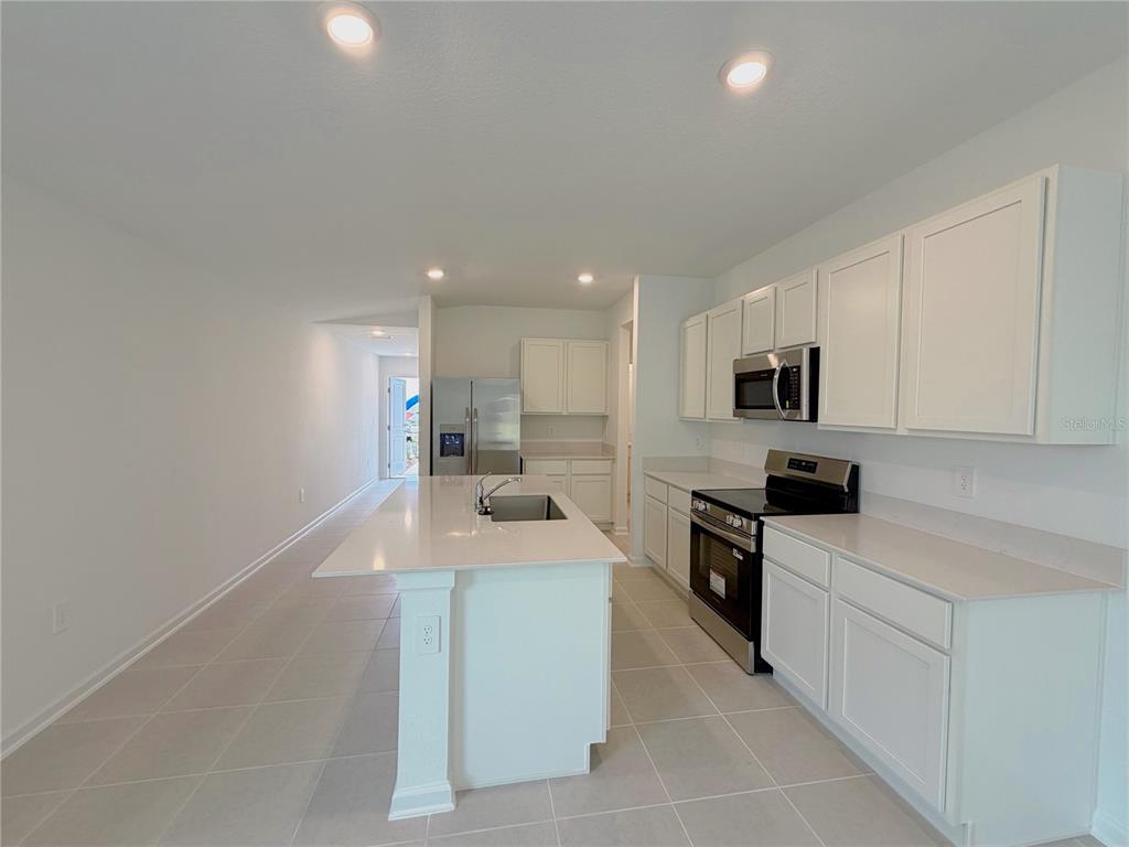 2154 Lasso Loop Eagle Lake, FL 33839 - Photo 3 of 32 a large white kitchen with stainless steel appliances granite countertop a sink dishwasher a stove and white cabinets with wooden floor