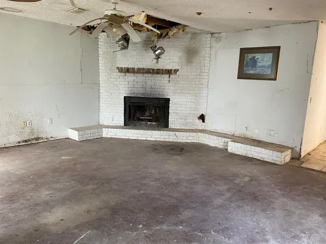an empty room with a fireplace and fan