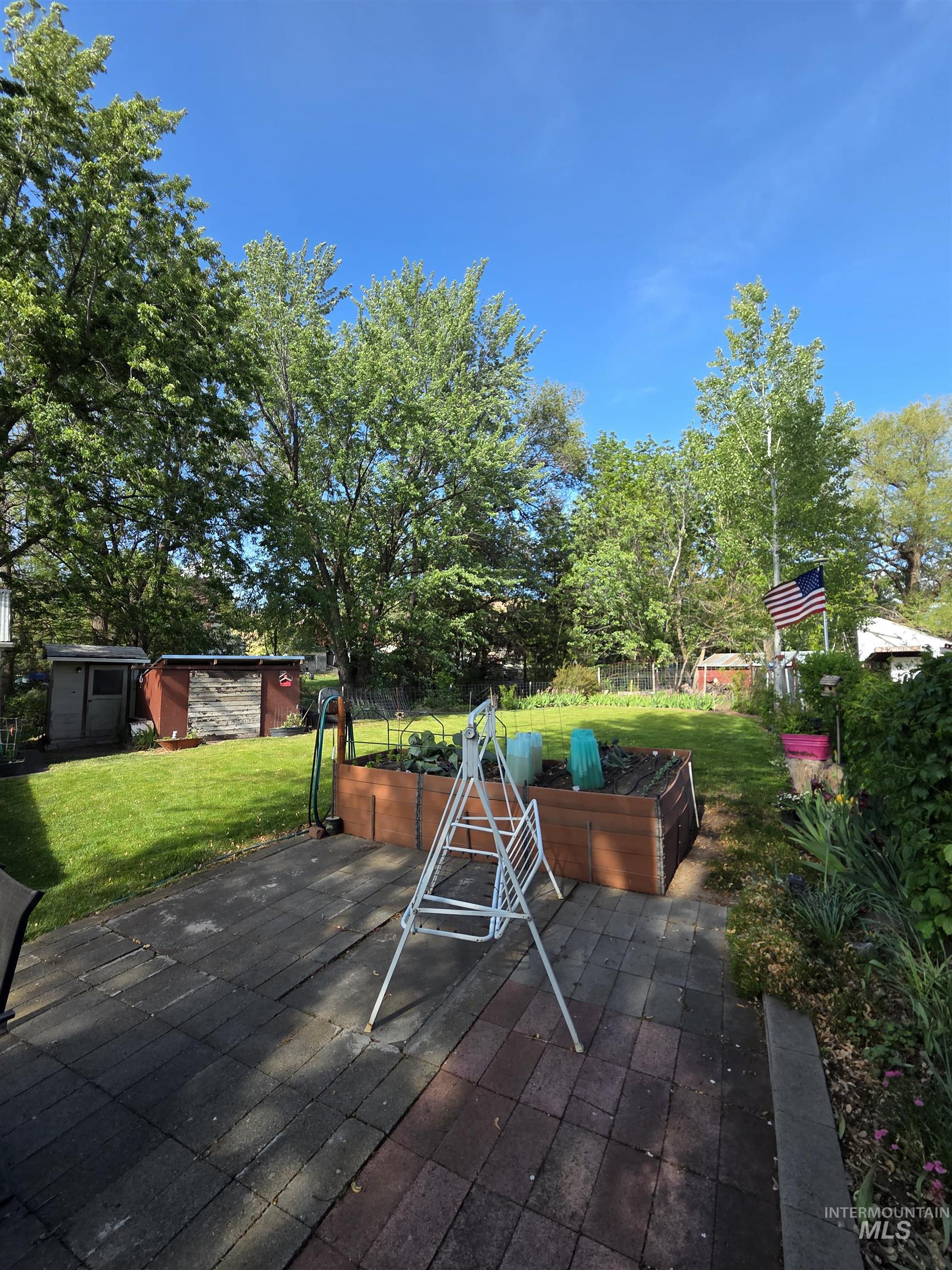109 South 3rd Street Pomeroy, WA 99347 - Photo 34 of 36 Expansive backyard featuring a paver patio, a raised garden bed, and a manicured lawn framed by mature trees