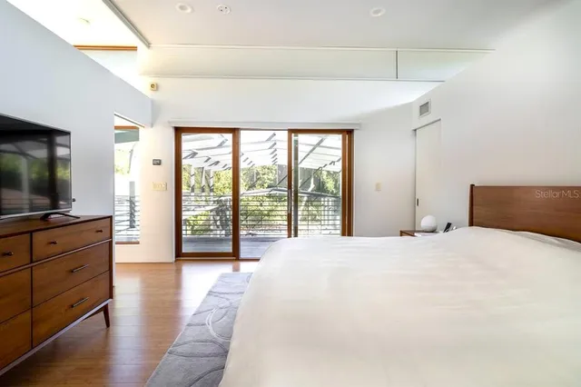 a spacious bedroom with a large bed and a flat tv screen on dresser