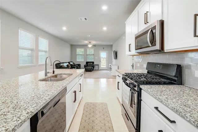 a kitchen with stainless steel appliances granite countertop a sink stove and cabinets