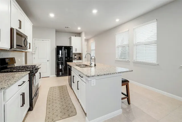 a kitchen with stainless steel appliances granite countertop a sink stove microwave and refrigerator