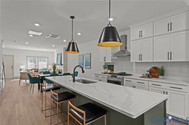 a kitchen with stainless steel appliances a stove a sink a kitchen island with a table and chairs