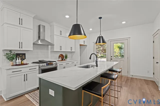 a kitchen with stainless steel appliances granite countertop a stove a sink dishwasher a refrigerator white cabinets and wooden floor