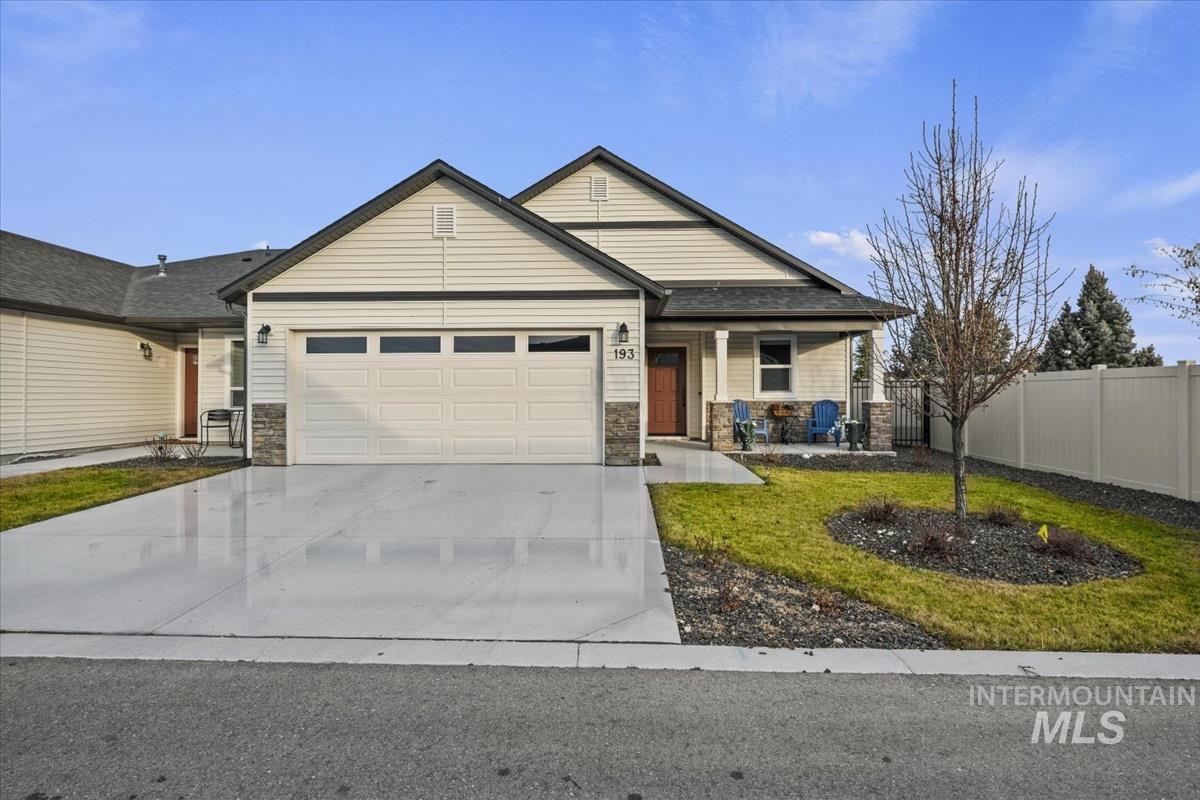 View of front of property featuring driveway, a porch, an attached garage, and stone siding