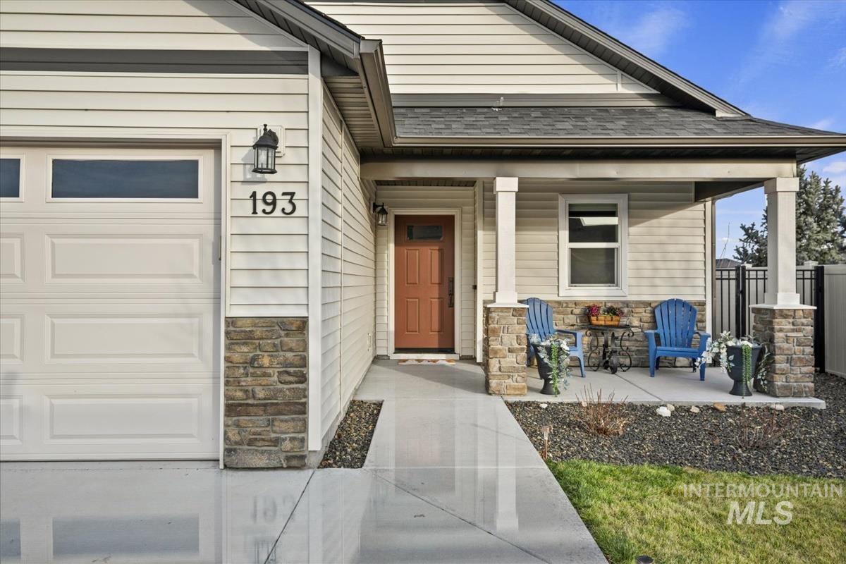193 West Haniken Street Meridian, ID 83642 - Photo 2 of 27 Entrance to property featuring stone siding, covered porch, and roof with shingles