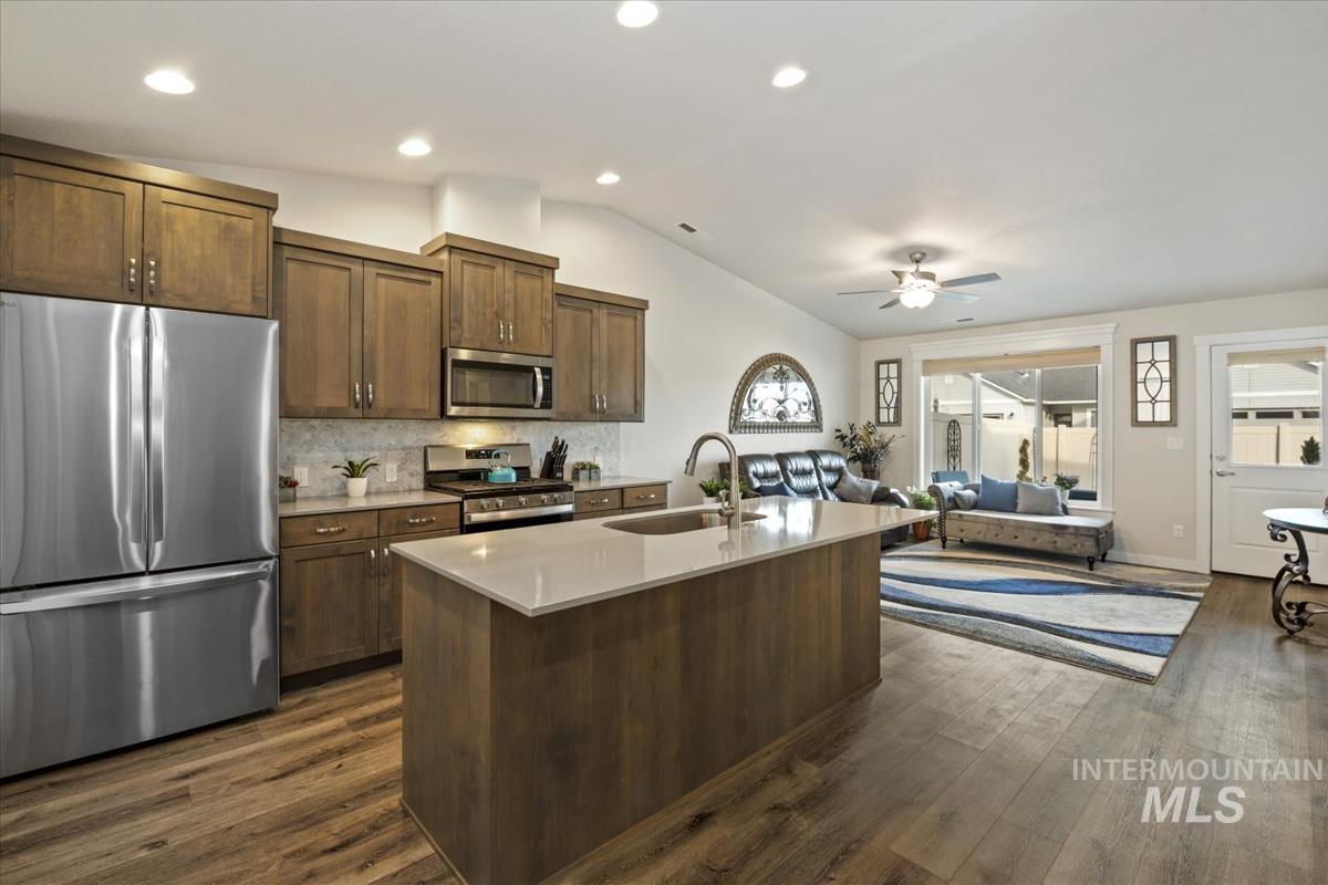 193 West Haniken Street Meridian, ID 83642 - Photo 25 of 27 Kitchen with stainless steel appliances, decorative backsplash, vaulted ceiling, dark wood finished floors, and open floor plan