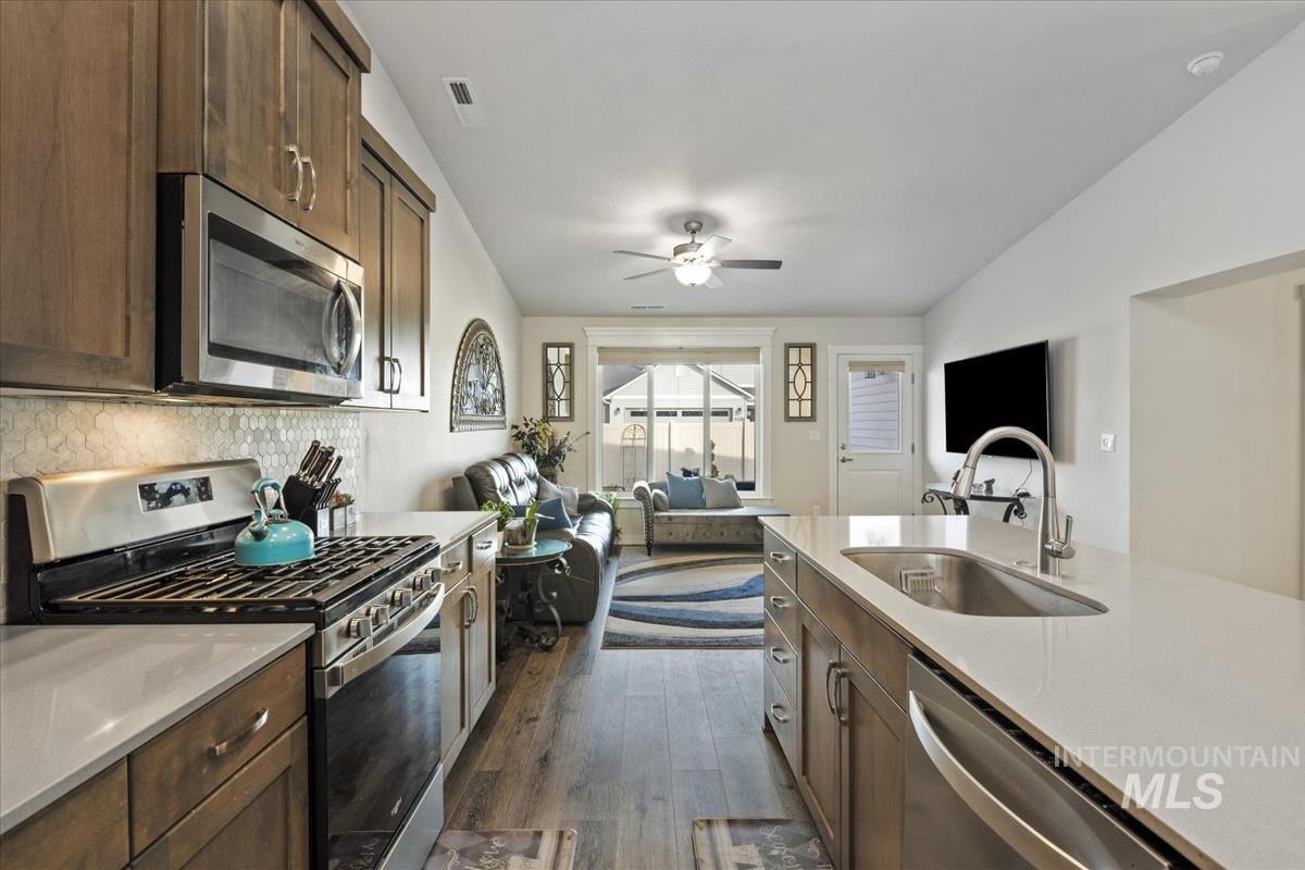 193 West Haniken Street Meridian, ID 83642 - Photo 26 of 27 Kitchen featuring stainless steel appliances, open floor plan, dark wood finished floors, ceiling fan, and light stone countertops
