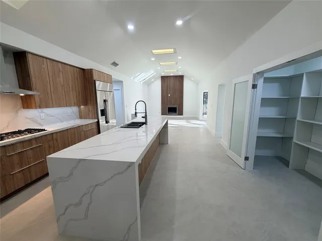 a large kitchen with kitchen island a sink stainless steel appliances and cabinets