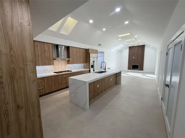 a large kitchen with stainless steel appliances a sink a counter top space cabinets and a window