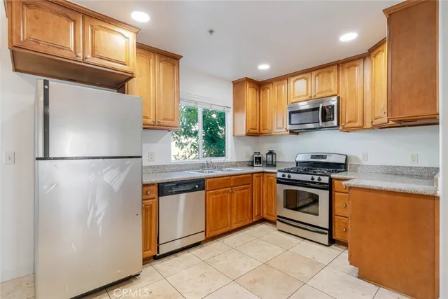 a kitchen with stainless steel appliances granite countertop a refrigerator a stove top oven a sink and dishwasher