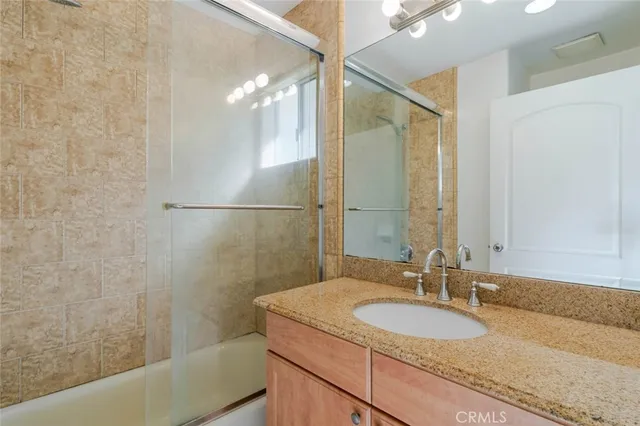 a bathroom with a granite countertop sink a mirror and a shower