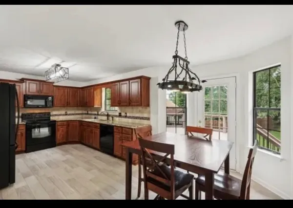 a kitchen with stainless steel appliances granite countertop a stove top oven a sink dishwasher a dining table and chairs with wooden floor