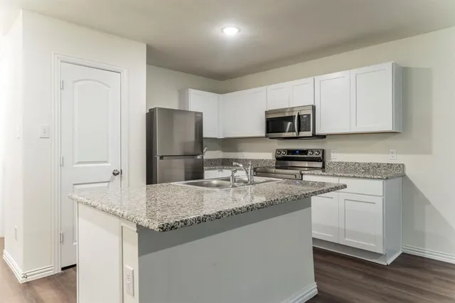 a kitchen with stainless steel appliances granite countertop a refrigerator stove top oven and sink