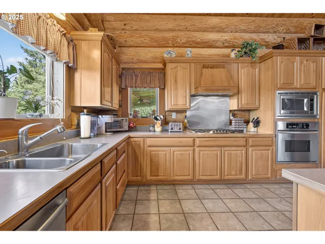a kitchen with stainless steel appliances granite countertop a refrigerator a stove and a sink with wooden cabinets