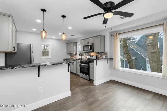 a kitchen with stainless steel appliances kitchen island a white cabinets and a wooden floor