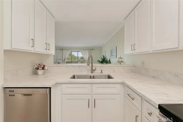 a kitchen with stainless steel appliances granite countertop a sink white cabinets and a sink