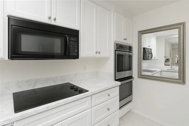 a kitchen with white cabinets and black appliances