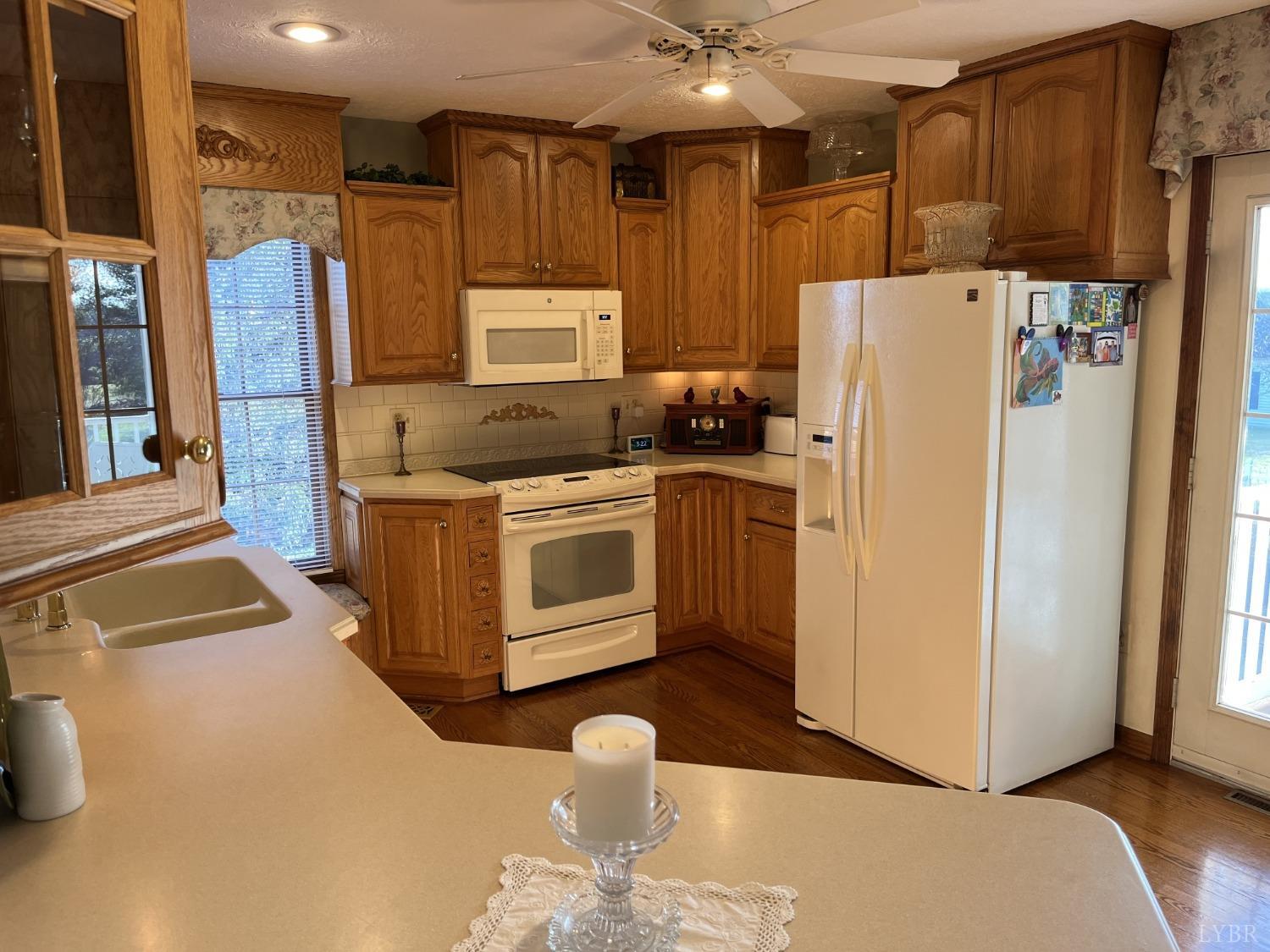 3912 Lowry Road Goode, VA 24556 - Photo 11 of 56 a kitchen with stainless steel appliances granite countertop a refrigerator a stove and a sink with wooden floor