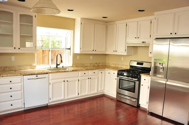 a kitchen with granite countertop white cabinets and stainless steel appliances