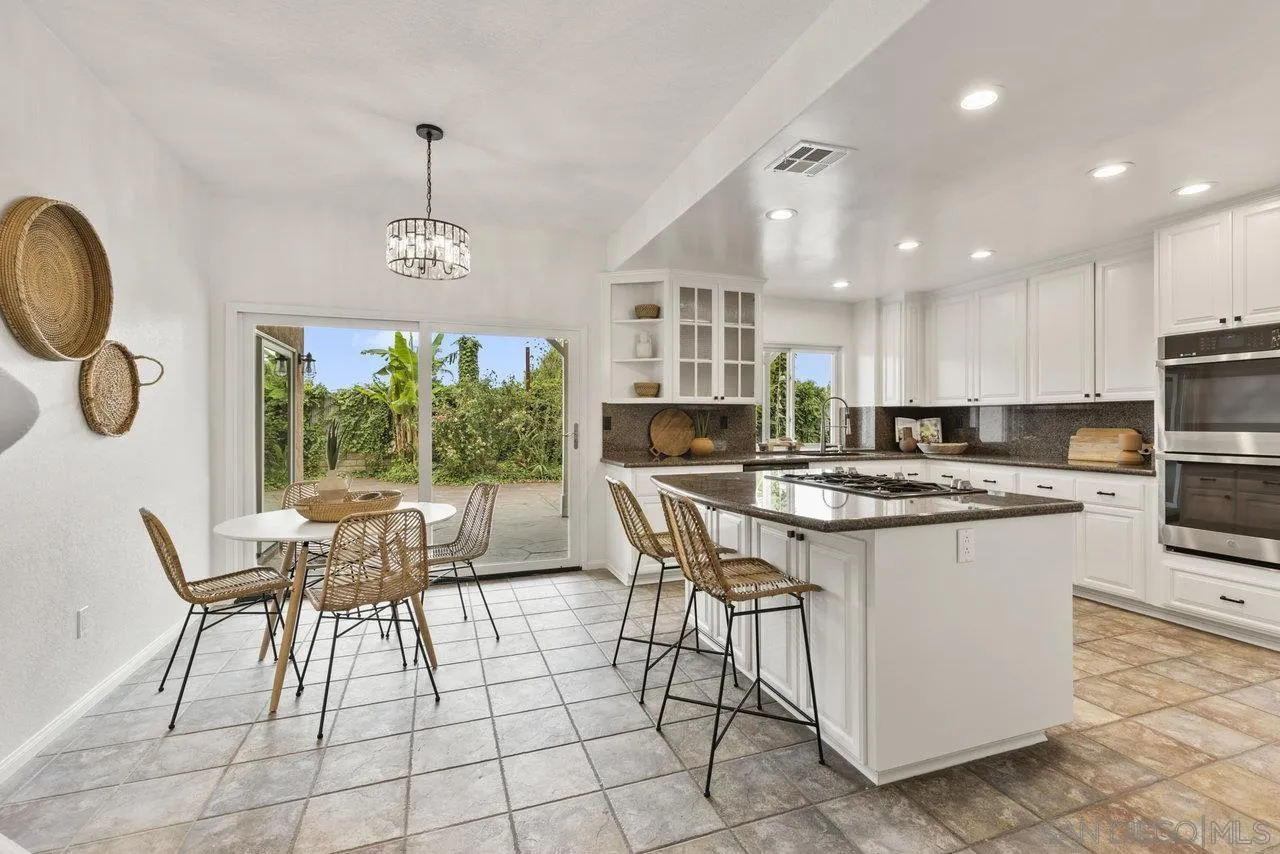 1363 Corte Alveo Oceanside, CA 92057 - Photo 15 of 62 a kitchen with stainless steel appliances granite countertop a stove top oven a sink dishwasher a dining table and chairs with wooden floor