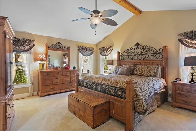 a spacious bedroom with a bed a dresser and a chandelier