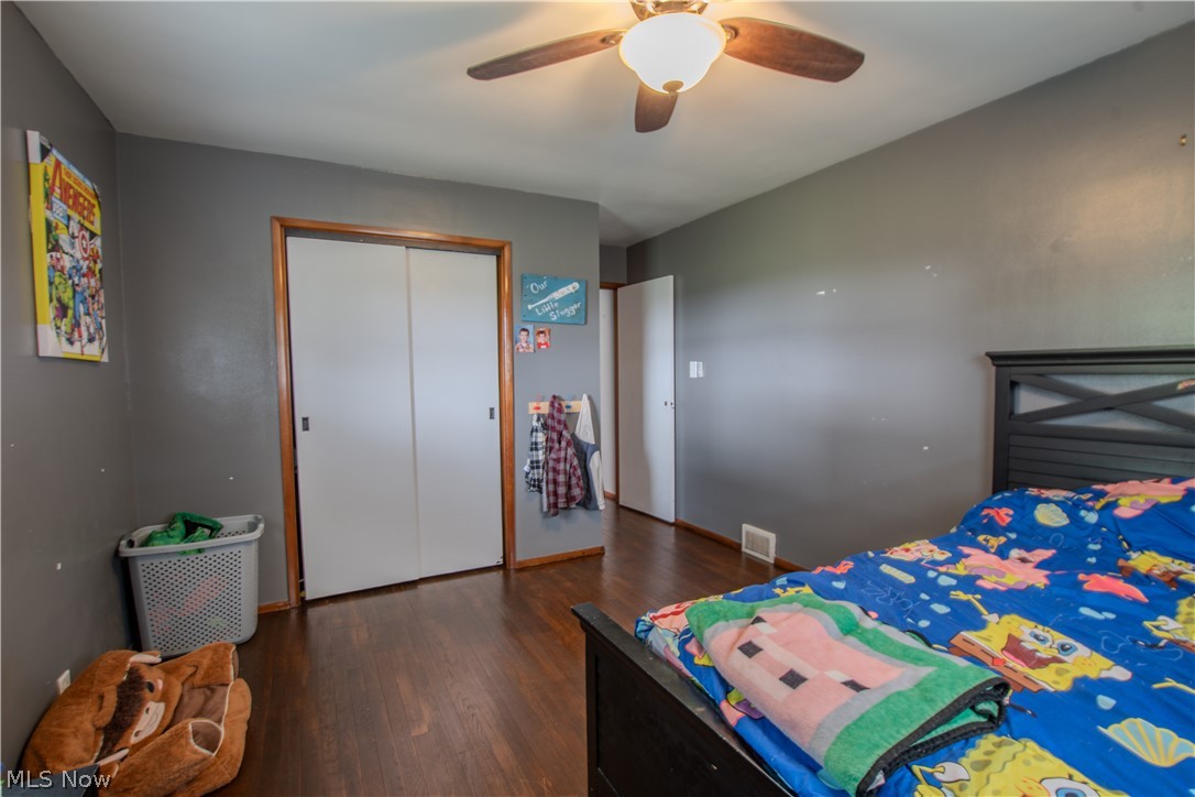1757 Pleasant Valley Road Northeast New Philadelphia, OH 44663 - Photo 27 of 33 Bedroom featuring wood-finish flooring, a ceiling fan with integrated lighting, and a bi-fold closet door with wood trim