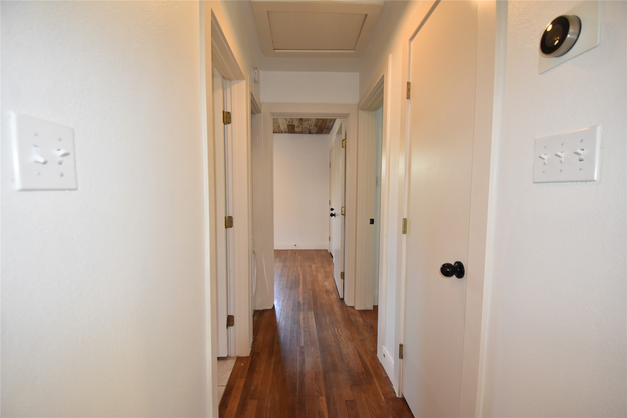 2012 Payne Avenue, Unit A Austin, TX 78757 - Photo 16 of 33 Hallway featuring hardwood flooring, white walls, multiple doorways, and a nest thermostat