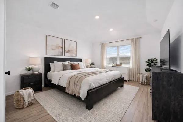 a bedroom with a bed and a flat tv screen on dresser