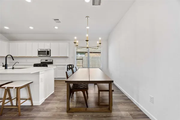 a kitchen with stainless steel appliances a stove top oven a sink dishwasher and a refrigerator with wooden floor