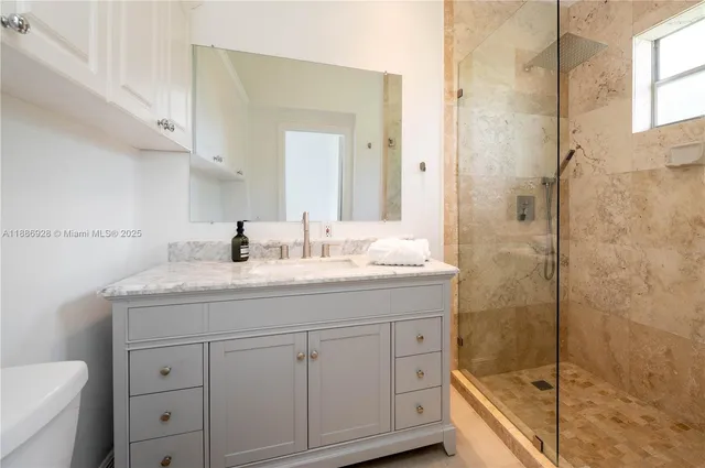 a bathroom with a granite countertop sink a toilet and shower